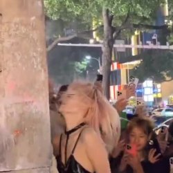 Chinesa mamando na rua em meio a multidão de gente